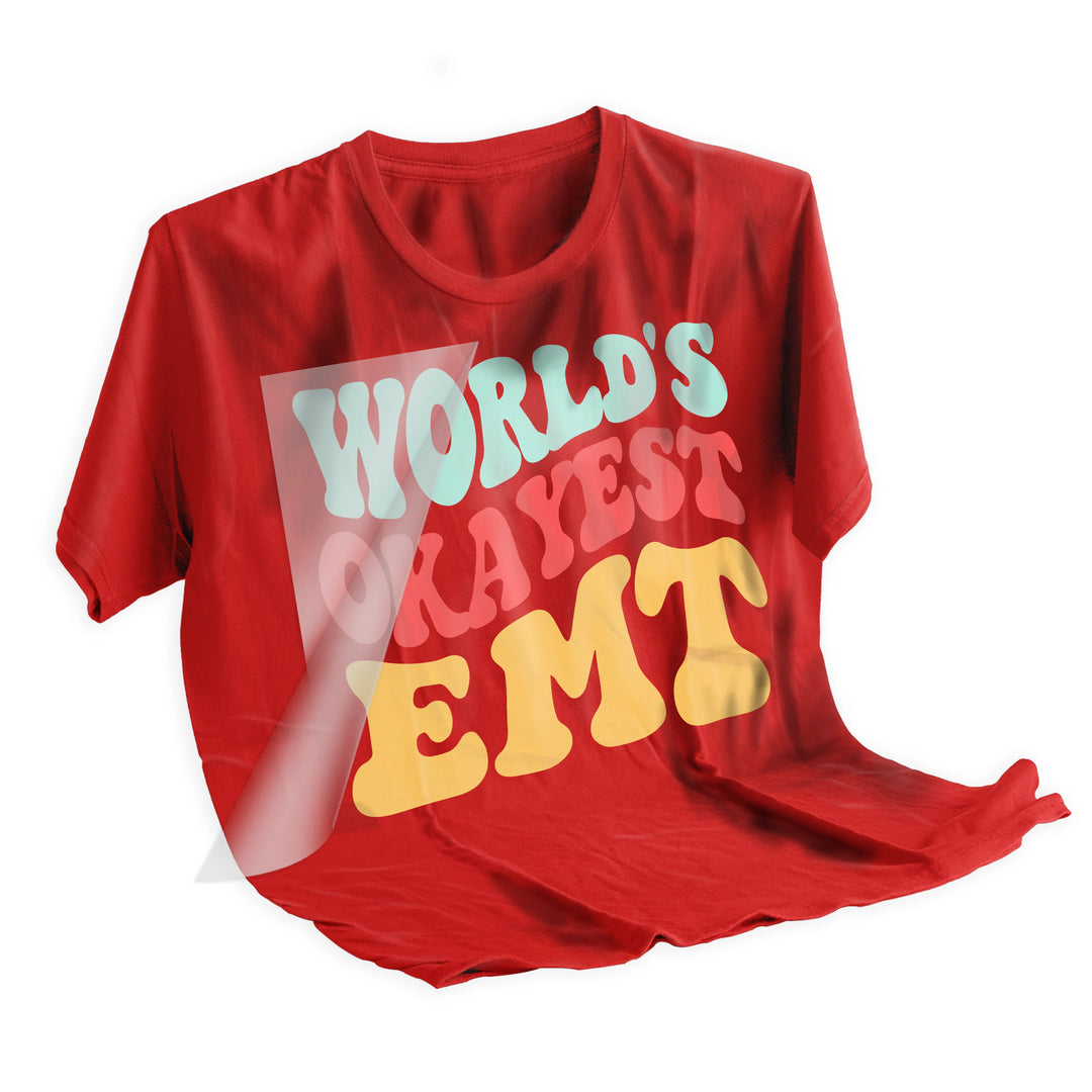World's Okayest EMT DTF transfer heat pressed onto dark colored t-shirt showing final application results